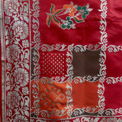 Red silk saree close-up with silver zari floral embroidery and patterned border