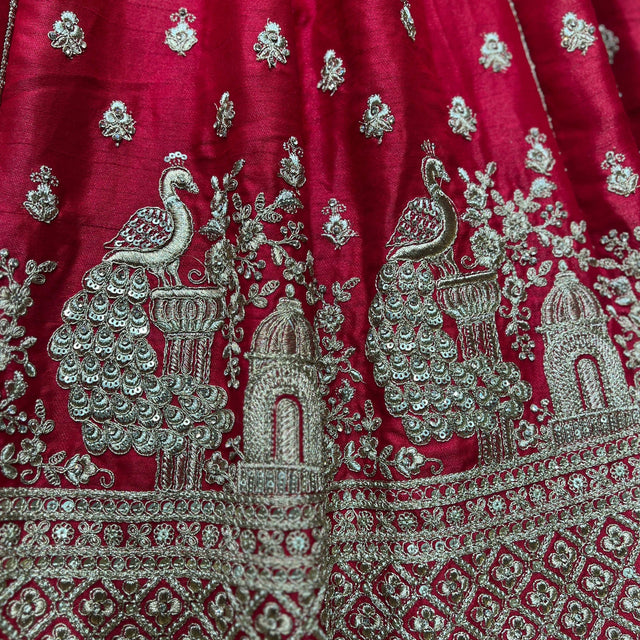 Red fabric with silver peacock-and-palace motifs and ornate embroidered border