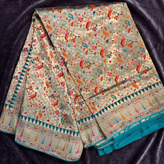 Sage green viscose saree with scattered parrot motifs and teal and gold border, draped