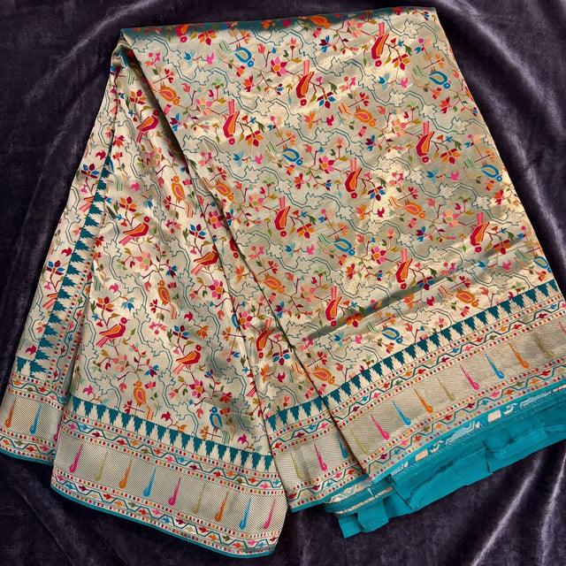 Sage green viscose saree with scattered parrot motifs and teal and gold border, draped