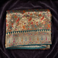 Sage green viscose saree with parrot-style motifs and teal temple border, folded view