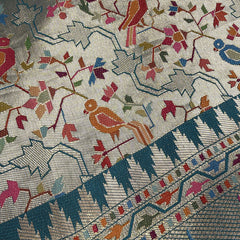 Sage green saree fabric close-up with bird jaal print and teal geometric border strip