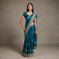 Teal blue tissue saree with gold zari-stone border, draped