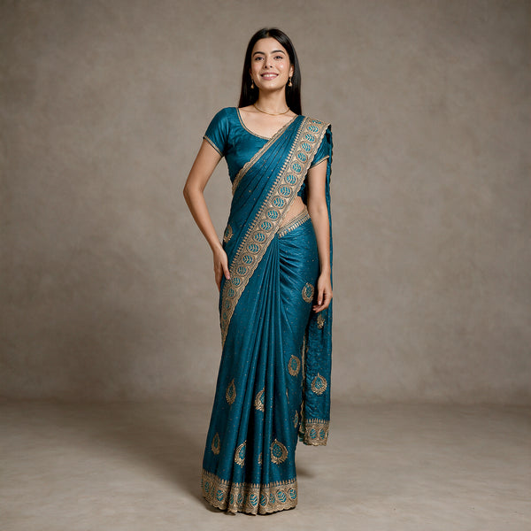 Teal blue tissue saree with gold zari-stone border, draped