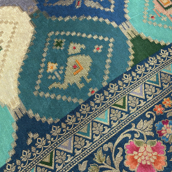 Teal blue saree fabric with geometric elephant motifs and ornate floral border