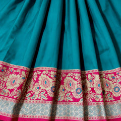 Teal pleated saree with rani pink floral band and decorative woven border