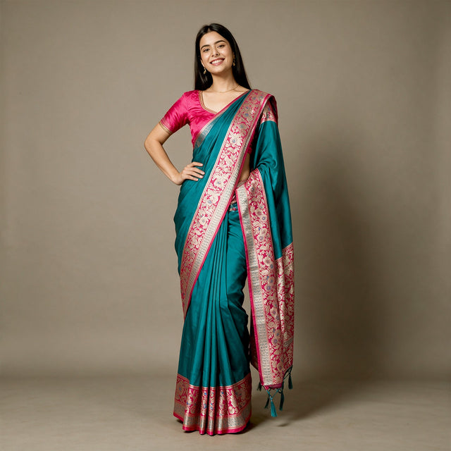 Teal art silk saree with rani pink floral border and patterned pallu, draped
