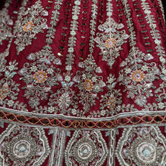 Red lehenga fabric close-up with silver mirror and pearl motifs, ornate embroidery